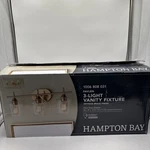 Hampton Bay Pavlen 24 In. 3-LIGHTS Antique Brass Vanity With Clear Glass. Fixed Price $40.00.